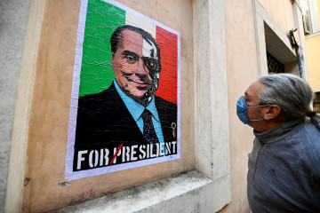 Un hombre contempla un mural de Silvio Berlusconi en Roma